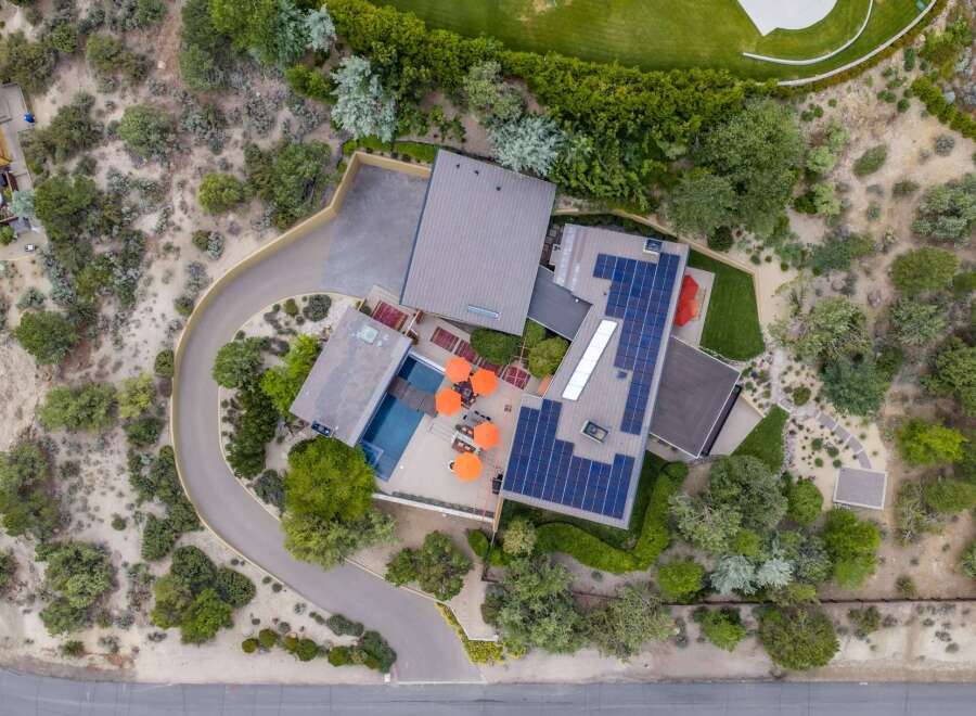 Experience modern luxury with this stunning aerial view of a contemporary home featuring a sparkling swimming pool and vibrant orange umbrellas.