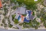 Experience modern luxury with this stunning aerial view of a contemporary home featuring a sparkling swimming pool and vibrant orange umbrellas.