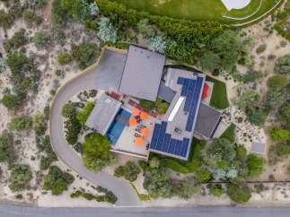 Experience modern luxury with this stunning aerial view of a contemporary home featuring a sparkling swimming pool and vibrant orange umbrellas.