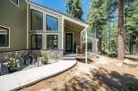 Nestled amidst tall pine trees, this charming home features a striking modern design with a mix of green siding and natural stone accents.