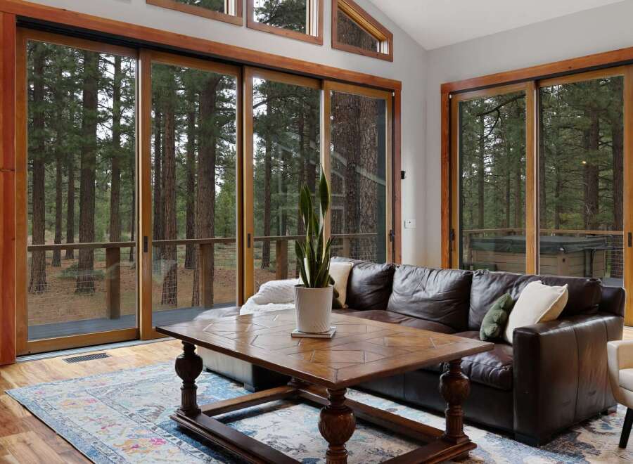Experience seamless indoor-outdoor living with expansive sliding glass doors that open to a serene forest backdrop.