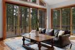 Experience seamless indoor-outdoor living with expansive sliding glass doors that open to a serene forest backdrop.