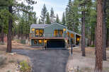 Nestled amidst tall pine trees, this modern home offers a serene retreat with its striking green exterior and expansive windows.