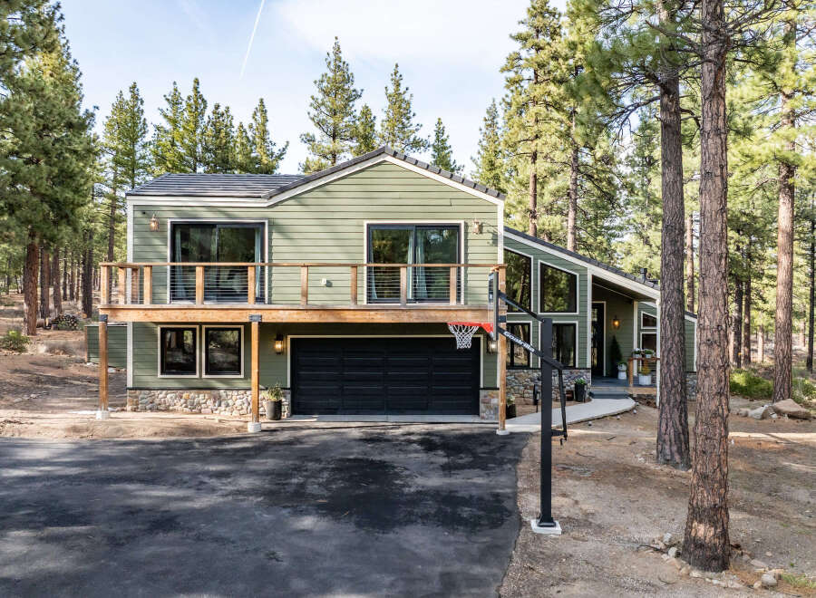 Experience modern mountain living in this stunning green home nestled among tall pine trees.