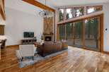 Experience luxury living in this stunning great room, featuring a floor-to-ceiling stone fireplace and expansive windows that showcase breathtaking forest views.