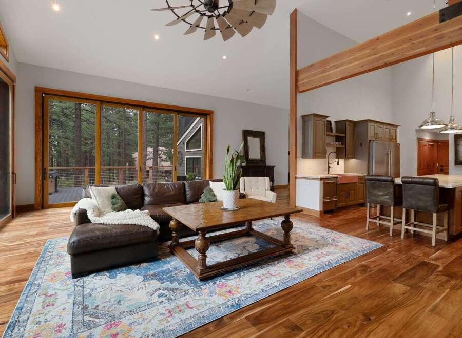 Experience luxurious living in this stunning open-concept home, featuring a spacious living area with a large leather sectional and a rustic wooden coffee table, perfect for gatherings.