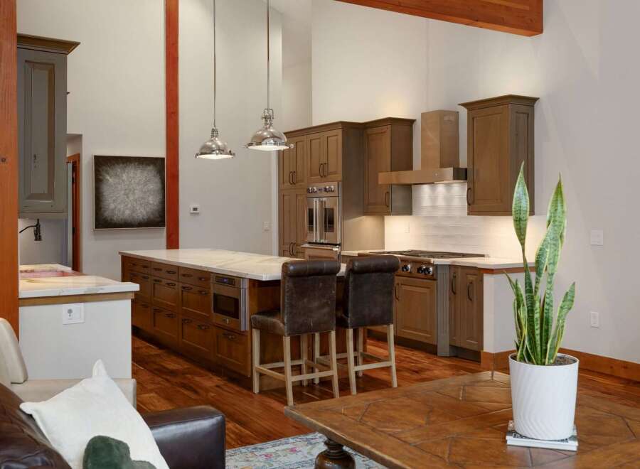 Experience luxury living in this stunning modern kitchen, featuring rich wood cabinetry, a spacious island with marble countertops, and top-of-the-line stainless steel appliances.
