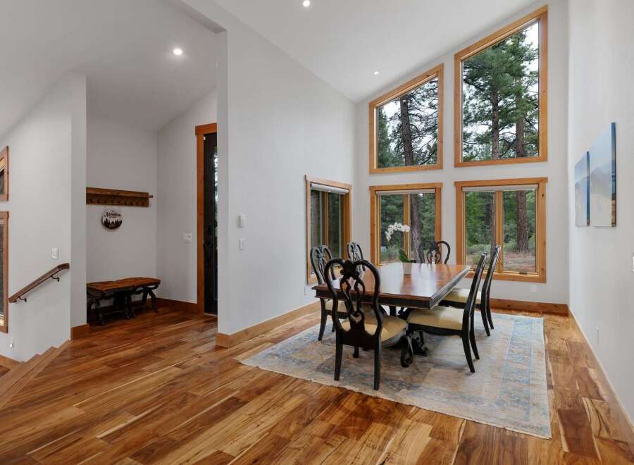 Experience breathtaking natural beauty from this stunning dining room, featuring expansive windows that frame the majestic pine forest.