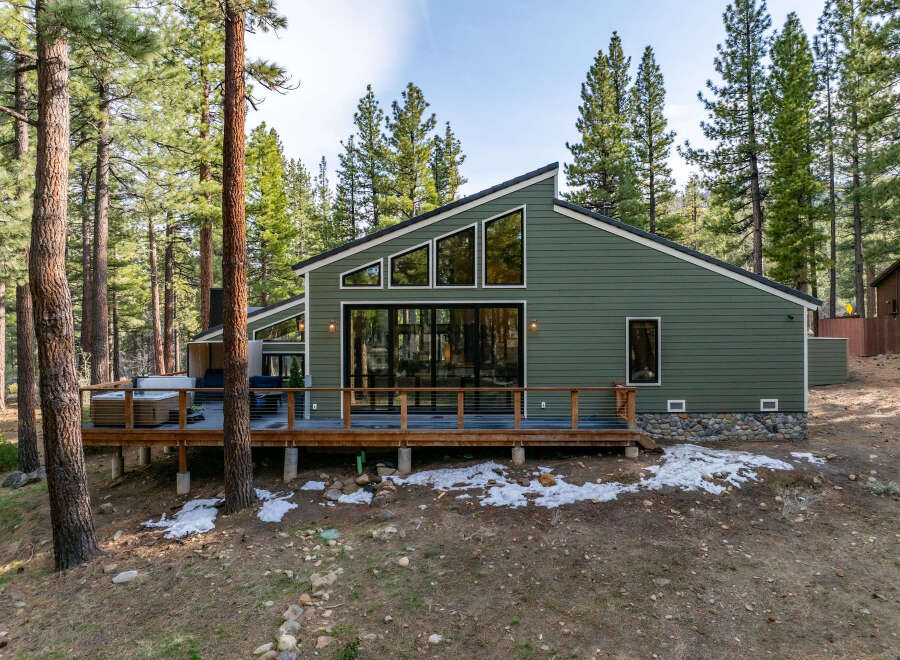 Experience modern mountain living in this stunning green home nestled among tall pine trees.