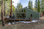Experience modern mountain living in this stunning green home nestled among tall pine trees.