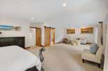 Experience luxury and comfort in this spacious master suite, featuring a cozy seating area perfect for relaxation.