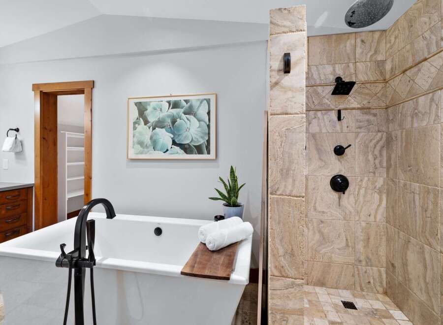 Indulge in relaxation with this luxurious bathroom featuring a freestanding soaking tub and a spacious walk-in shower with elegant travertine tile.