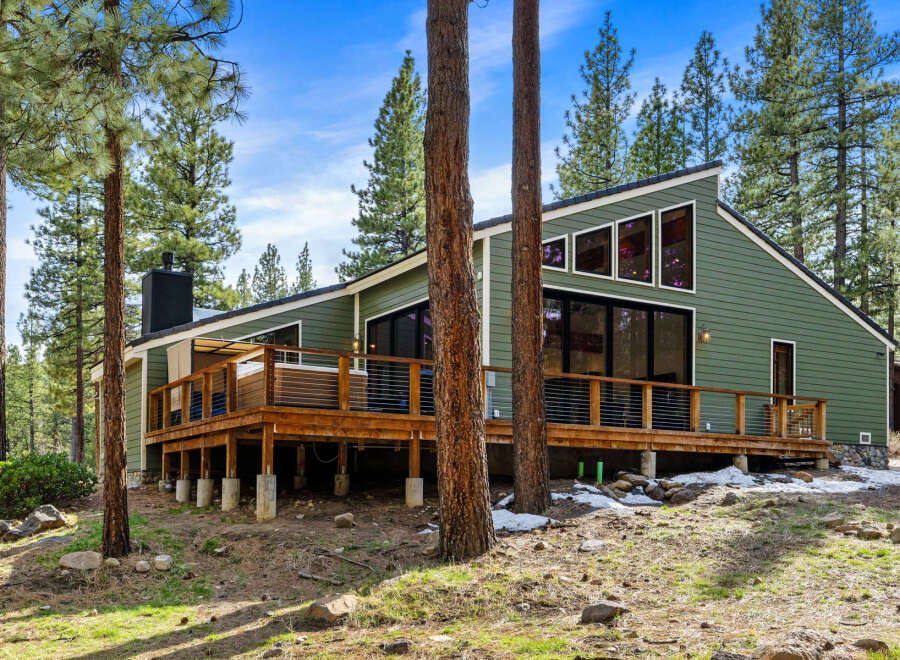 Experience modern mountain living in this stunning green home, nestled amongst tall pine trees.