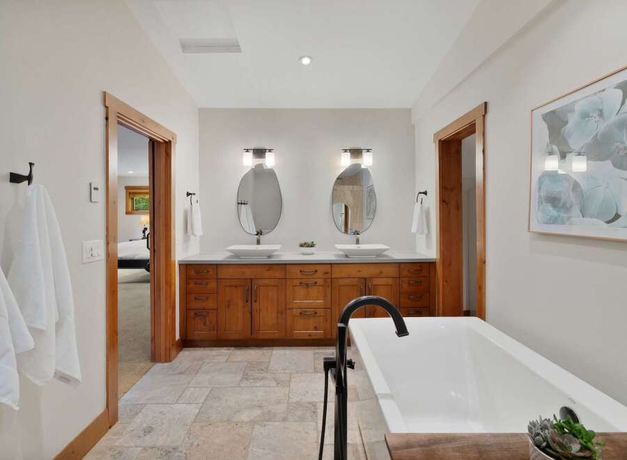 Experience luxury in this stunning bathroom featuring a freestanding soaking tub and a spacious double vanity with vessel sinks.