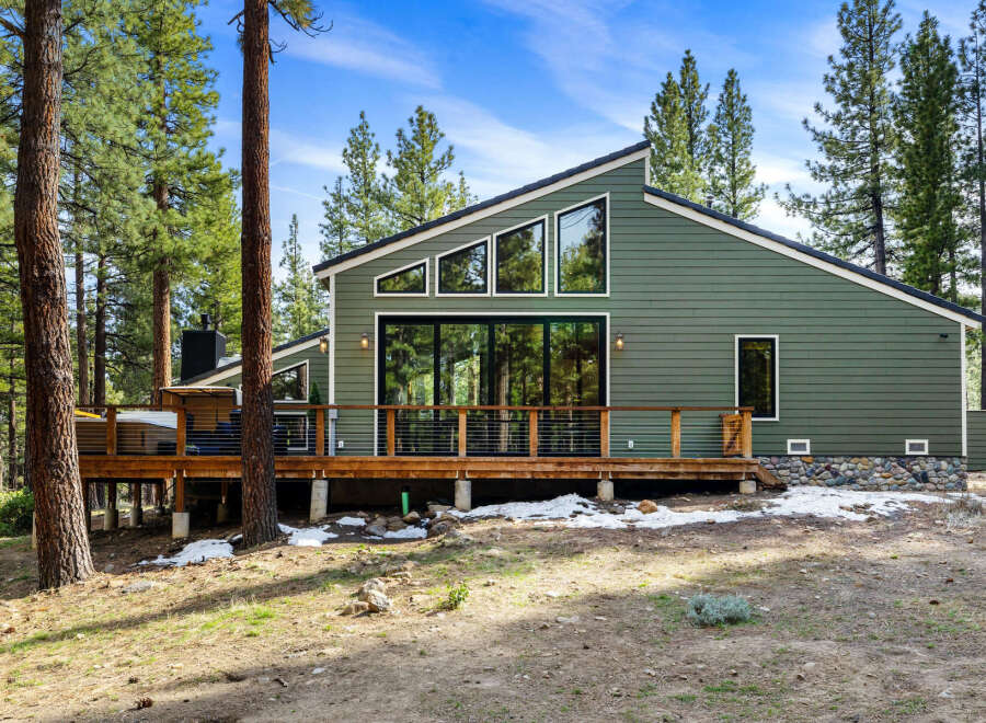 Experience modern mountain living in this stunning green home nestled among tall pine trees.