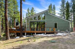 Experience modern mountain living in this stunning green home nestled among tall pine trees.