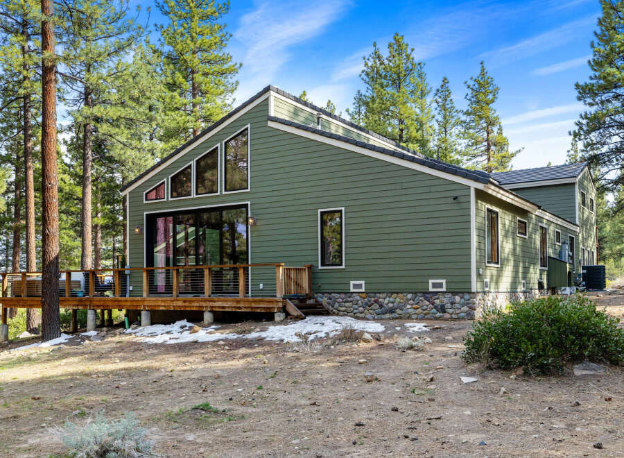 Nestled among tall pine trees, this charming green home offers a serene retreat.