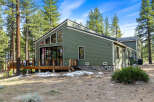 Nestled among tall pine trees, this charming green home offers a serene retreat.