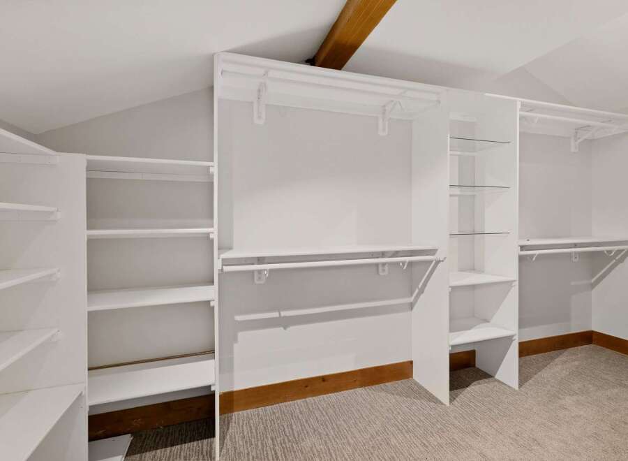 Discover ample storage in this spacious walk-in closet, featuring a versatile shelving system and multiple hanging rods.
