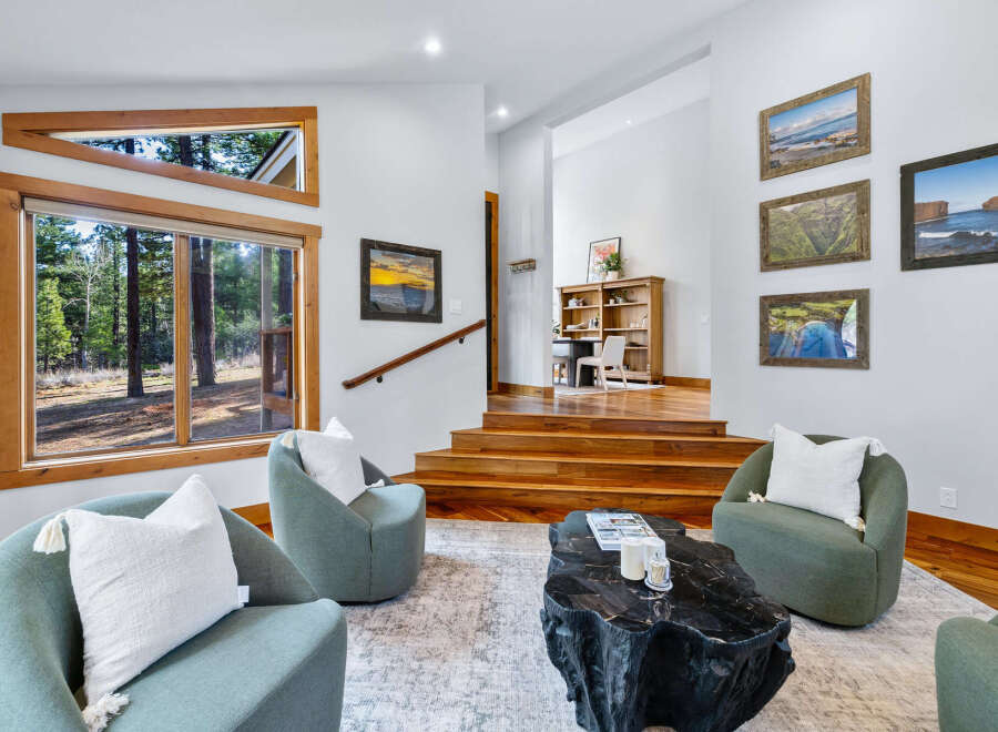 Experience modern living in this stunning home featuring a spacious living area with large windows offering picturesque forest views.