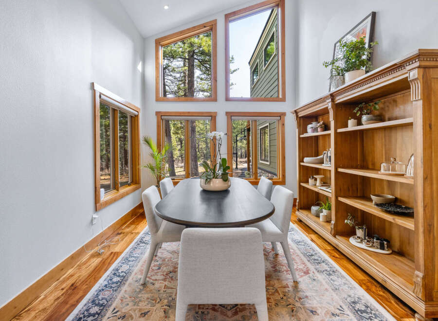Experience natural light and stunning forest views in this elegant dining room, featuring a large oval table perfect for gatherings.