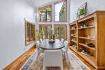 Experience natural light and stunning forest views in this elegant dining room, featuring a large oval table perfect for gatherings.
