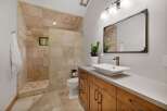 Experience luxury in this stunning bathroom featuring a spacious walk-in shower with elegant travertine tile and a charming window overlooking nature.