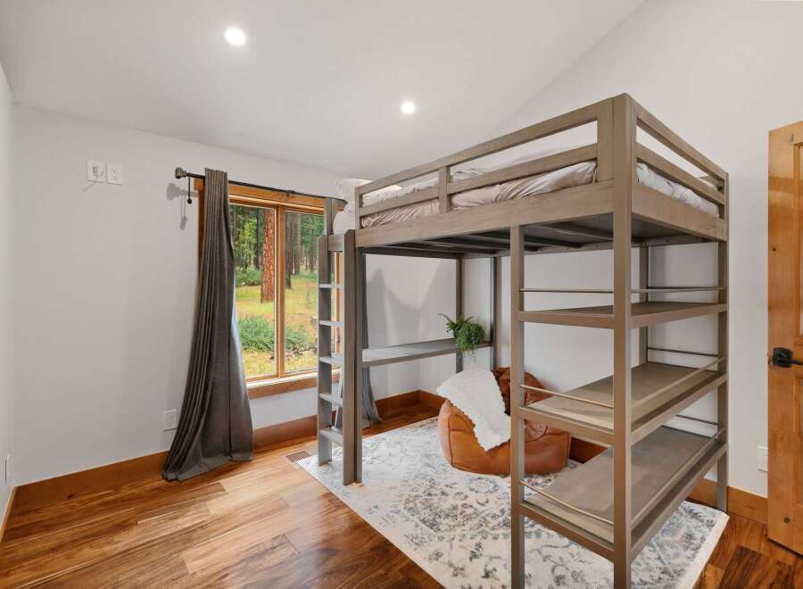 This bedroom features a space-saving loft bed with an integrated desk and shelving, perfect for maximizing room functionality.