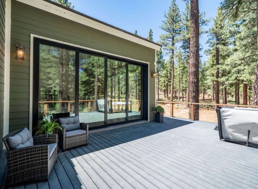 Enjoy the serene mountain lifestyle with this stunning deck featuring a relaxing hot tub and comfortable seating areas, perfect for unwinding amidst the towering pine trees.