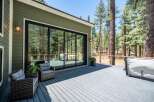 Enjoy the serene mountain lifestyle with this stunning deck featuring a relaxing hot tub and comfortable seating areas, perfect for unwinding amidst the towering pine trees.