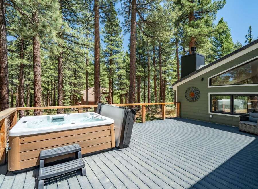 Enjoy ultimate relaxation on this spacious deck, featuring a luxurious hot tub perfect for unwinding amidst the serene forest setting.