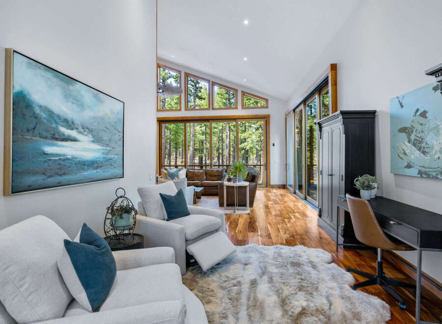 Experience luxurious living in this stunning home featuring a spacious living area with large windows offering breathtaking forest views.