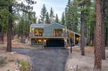 Nestled amidst tall pine trees, this modern home offers a serene retreat with its striking green exterior and expansive windows.