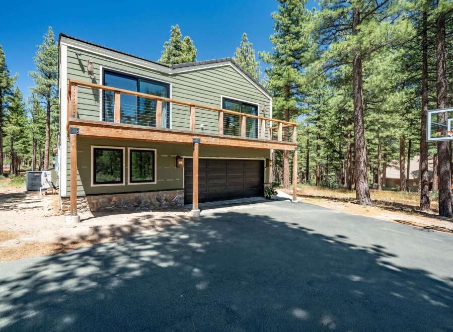 Experience modern mountain living in this stunning home, featuring a spacious deck perfect for enjoying the surrounding pine forest.
