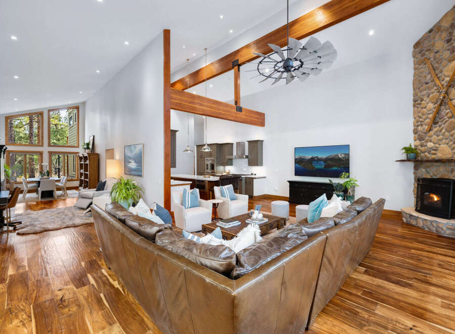 Experience luxurious mountain living in this stunning great room, featuring a soaring vaulted ceiling with exposed wooden beams and a rustic stone fireplace.
