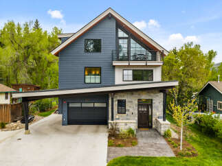 Experience modern mountain living in this stunning home featuring a striking architectural design with a mix of dark siding and stone accents.