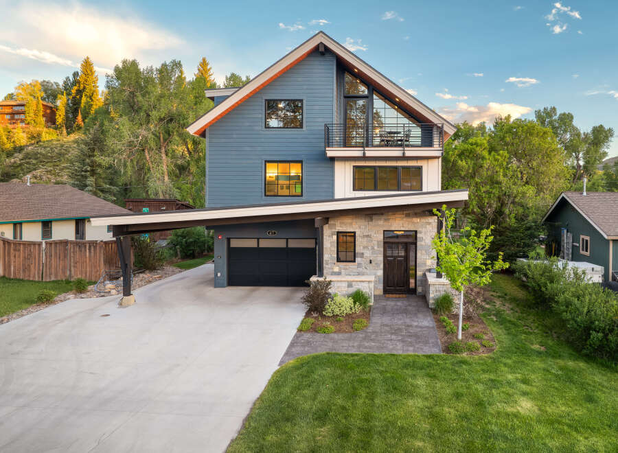 Experience modern mountain living in this stunning home featuring a striking blue exterior and a stone-clad entrance.