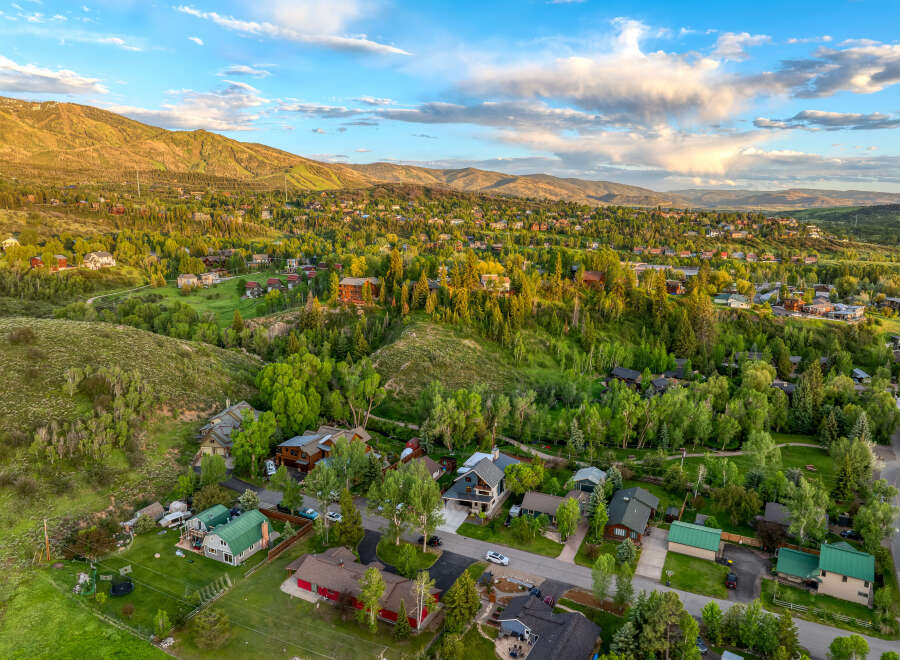 Nestled amidst lush greenery and rolling hills, this stunning aerial view showcases a charming neighborhood with a collection of beautiful homes.