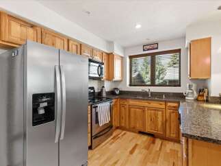 This charming kitchen boasts beautiful natural wood cabinetry and sleek stainless steel appliances, including a side-by-side refrigerator with an ice dispenser.