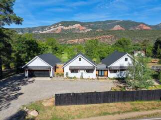 Experience modern farmhouse living with this stunning property, featuring a sleek white exterior and a dark metal roof.