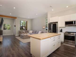 This modern open-concept living space features a spacious sectional sofa perfect for gatherings, complemented by a large window offering scenic views.