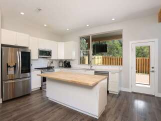 Experience modern living in this stunning kitchen featuring sleek white cabinetry and a spacious butcher block island perfect for meal prep and entertaining.