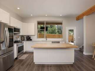 Experience modern living in this stunning kitchen featuring sleek white cabinetry and a spacious butcher block island perfect for meal prep and casual dining.