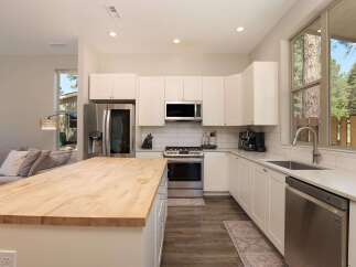 Experience modern living in this stunning kitchen featuring sleek white cabinetry, a spacious butcher block island, and stainless steel appliances.
