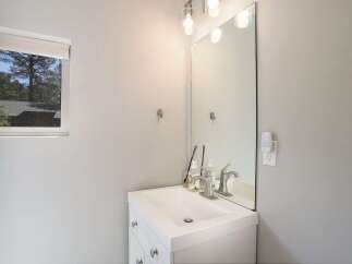 This modern bathroom features a sleek white vanity with a clean-lined sink and a brushed nickel faucet.