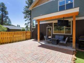 Enjoy outdoor living with this spacious patio featuring a paved brick floor and a covered seating area.