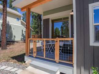 Charming porch with a modern wooden fence and wire mesh, offering a glimpse of a small bistro set perfect for enjoying the outdoors.