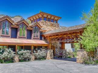 Experience luxury mountain living in this stunning custom-built home, featuring a striking stone and wood exterior that blends seamlessly with the natural landscape.