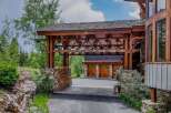 Experience rustic luxury with this stunning mountain home, featuring a grand porte-cochère with intricate wooden beams and stone accents.