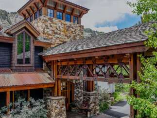 Experience rustic luxury in this stunning mountain home, featuring a unique stone and wood facade that blends seamlessly with the natural landscape.